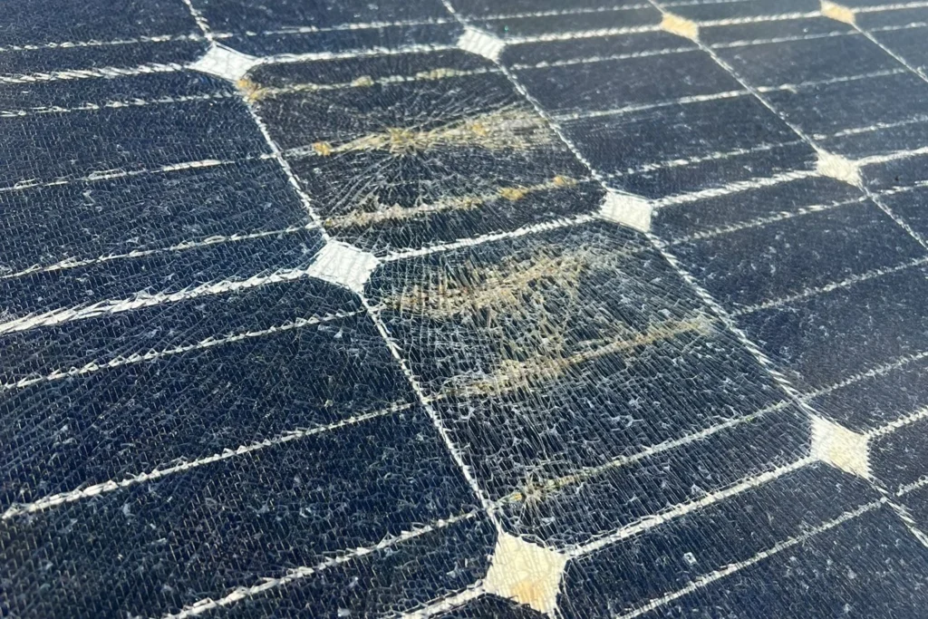Nahaufnahme von Solarzellen mit dichtem Netz feiner Risse und gelbbrauner Verfärbung darin